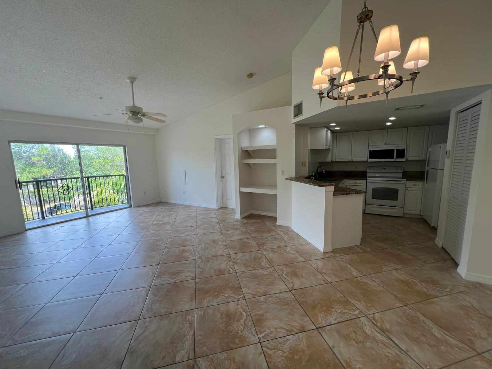 An open-concept living area with tile floors, a kitchen, and a balcony with outdoor views — 500 Crestwood Court N # 517, Royal Palm Beach FL 33411, ROYAL PALM BEACH, FL