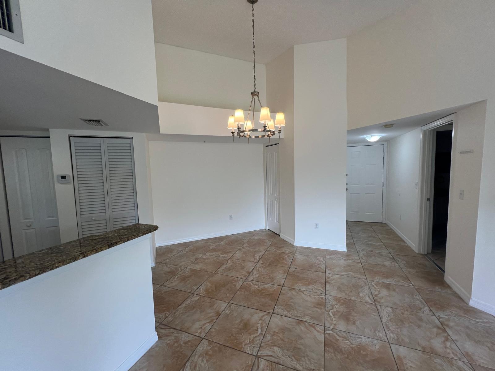 A dining area with tile flooring, a chandelier, and a granite-topped kitchen counter — 500 Crestwood Court N # 517, Royal Palm Beach FL 33411, ROYAL PALM BEACH, FL