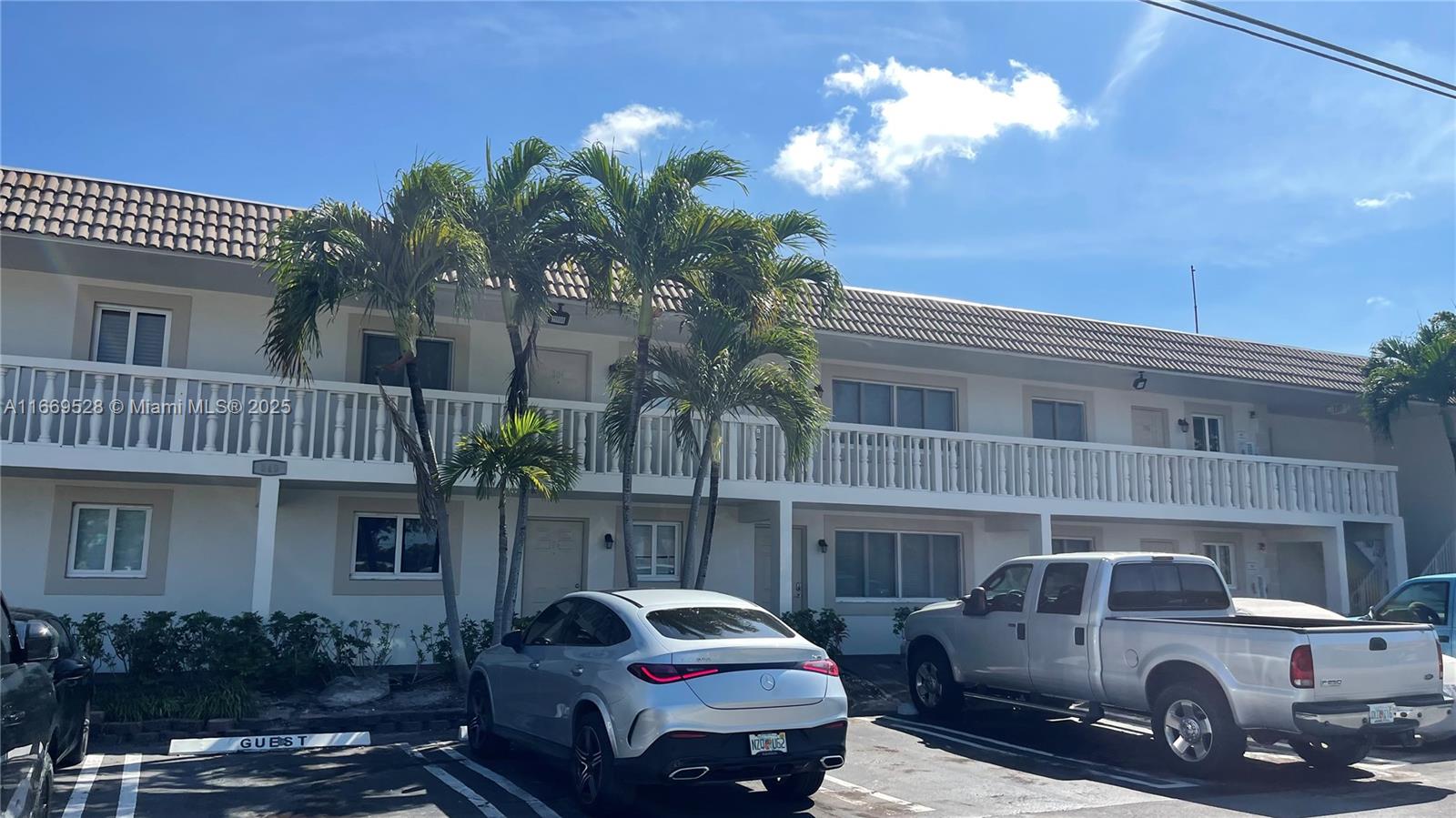 A two-story apartment building features a white exterior, a balcony, and a parking lot — 840 Pine Dr # 103, Pompano Beach FL 33060, POMPANO BEACH, FL