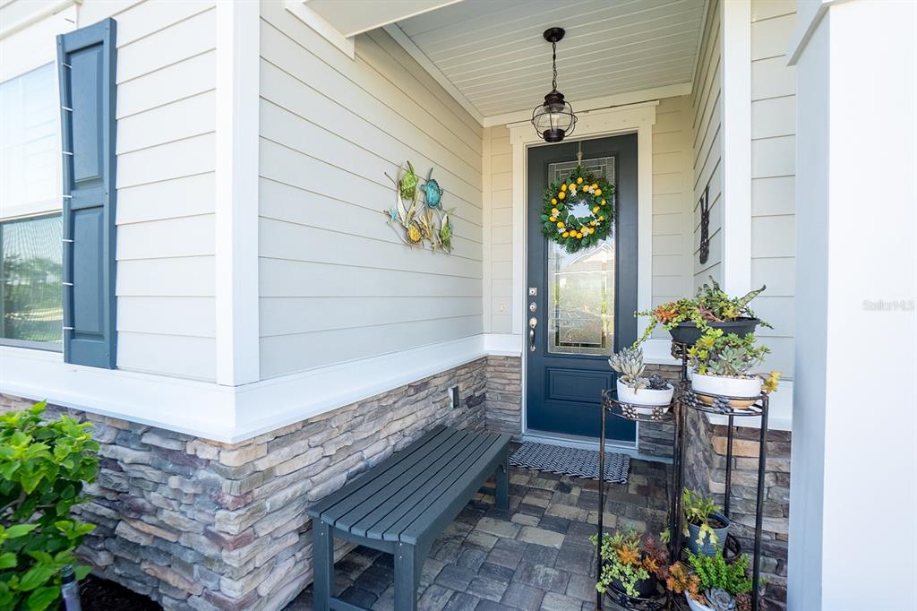 A front porch features a dark blue door, a stone base, and a wooden bench — 9 LOS LAGOS BOULEVARD, PALM COAST, FL