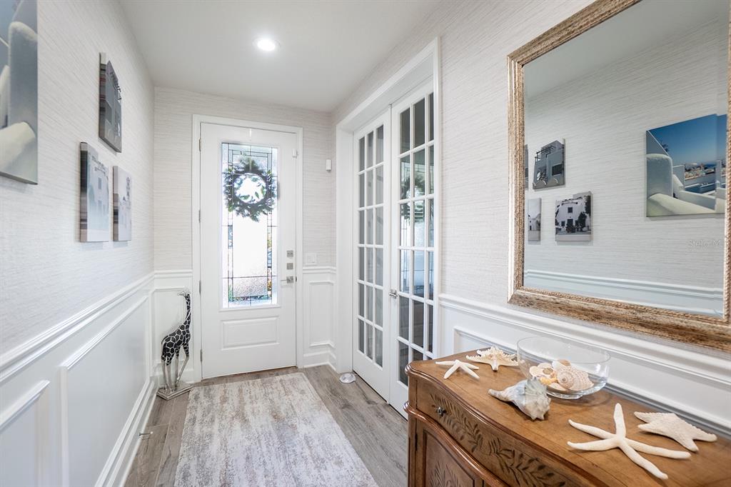 An entryway features a white front door, French doors, wainscoting, and a wooden console table — 9 LOS LAGOS BOULEVARD, PALM COAST, FL