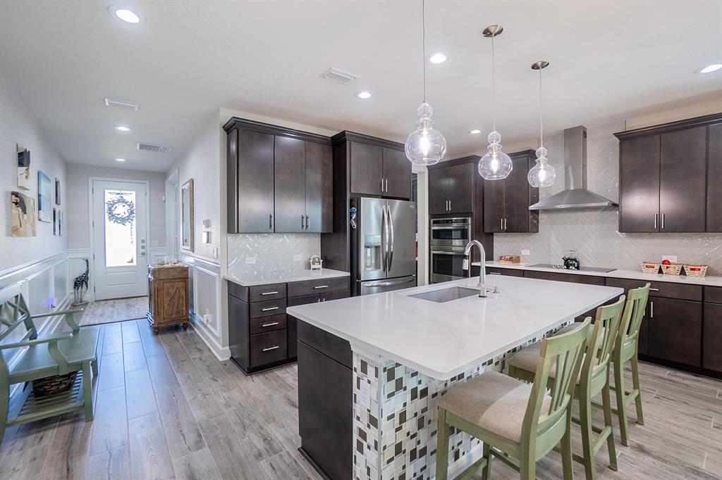 A modern kitchen features dark cabinetry, a white quartz island, and a tiled backsplash — 9 LOS LAGOS BOULEVARD, PALM COAST, FL