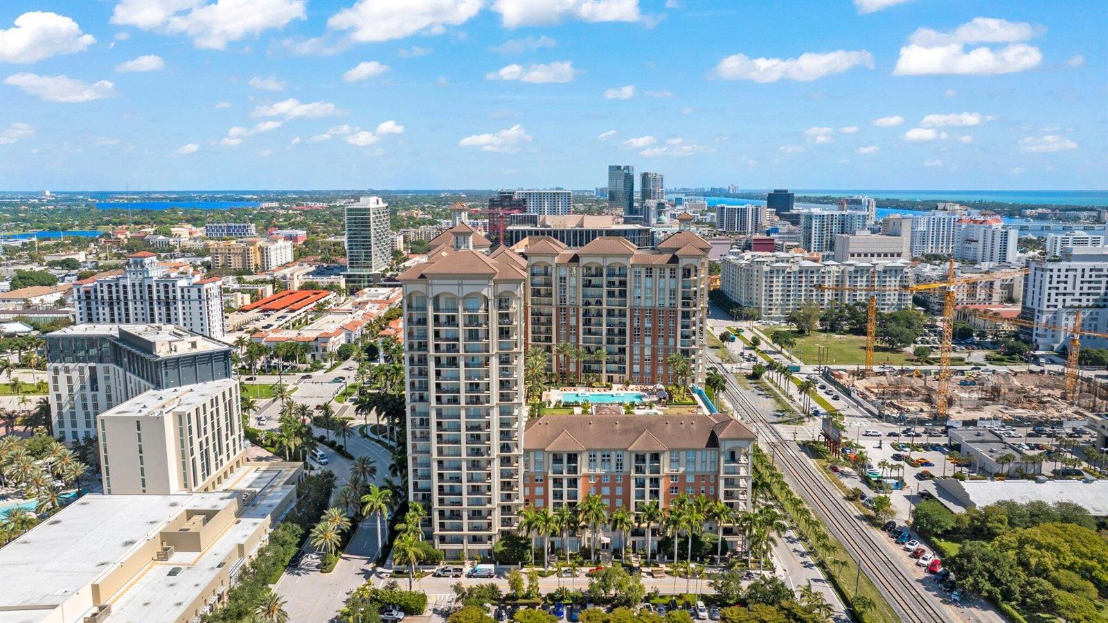 An aerial view of a large residential complex with a pool and surrounding city buildings — 550 Okeechobee Boulevard # 620, West Palm Beach FL 33401, WEST PALM BEACH, FL