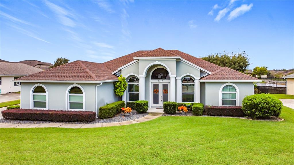 A single-story house with a light gray exterior, arched windows, and a brown shingled roof — 2808 DEERFIELD STREET, ST CLOUD, FL