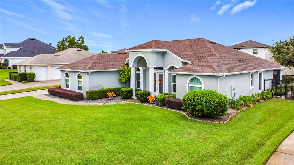 A light blue, single-story house with a brown shingled roof and manicured landscaping — 2808 DEERFIELD STREET, ST CLOUD, FL