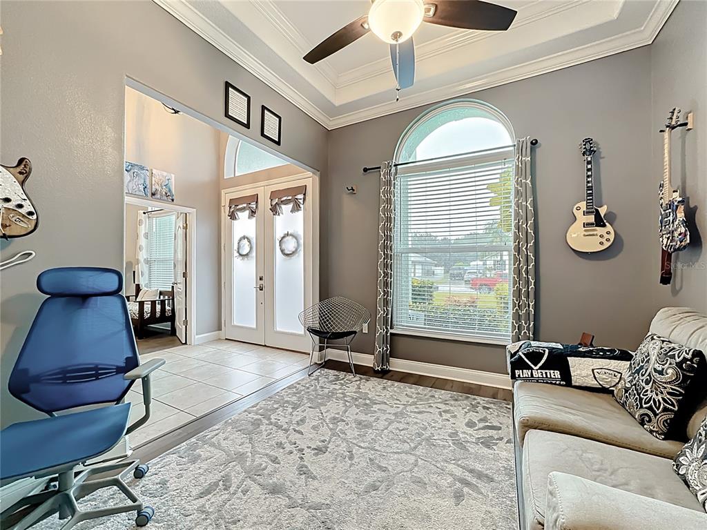 A living room with gray walls, a large arched window, and guitars mounted on the wall — 2808 DEERFIELD STREET, ST CLOUD, FL