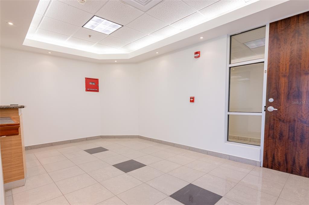 An empty office lobby features white walls, tile flooring with dark accents, and a wooden door — 995 METRO MEDICAL CENTER CLL REV DOM MARRERO, BAYAMON, PR