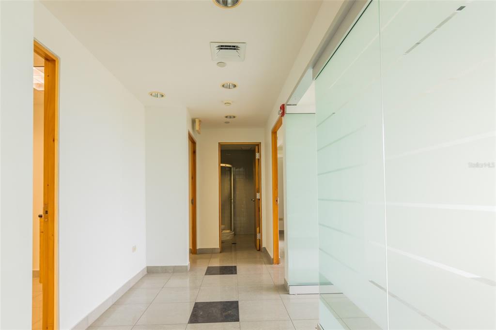 A brightly lit hallway features light-colored tile flooring, white walls, and several wooden door frames — 995 METRO MEDICAL CENTER CLL REV DOM MARRERO, BAYAMON, PR