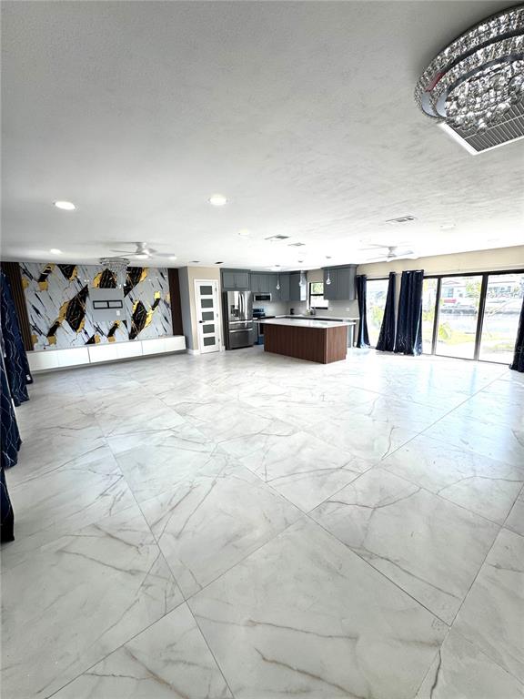 This open-concept living area features large marble-look floor tiles, a kitchen island, and decorative wall paneling — 10708 DONBRESE AVENUE, TAMPA, FL