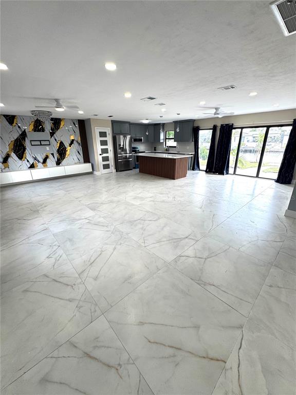 A spacious open-concept living area features large white marble-look floor tiles and a modern kitchen — 10708 DONBRESE AVENUE, TAMPA, FL