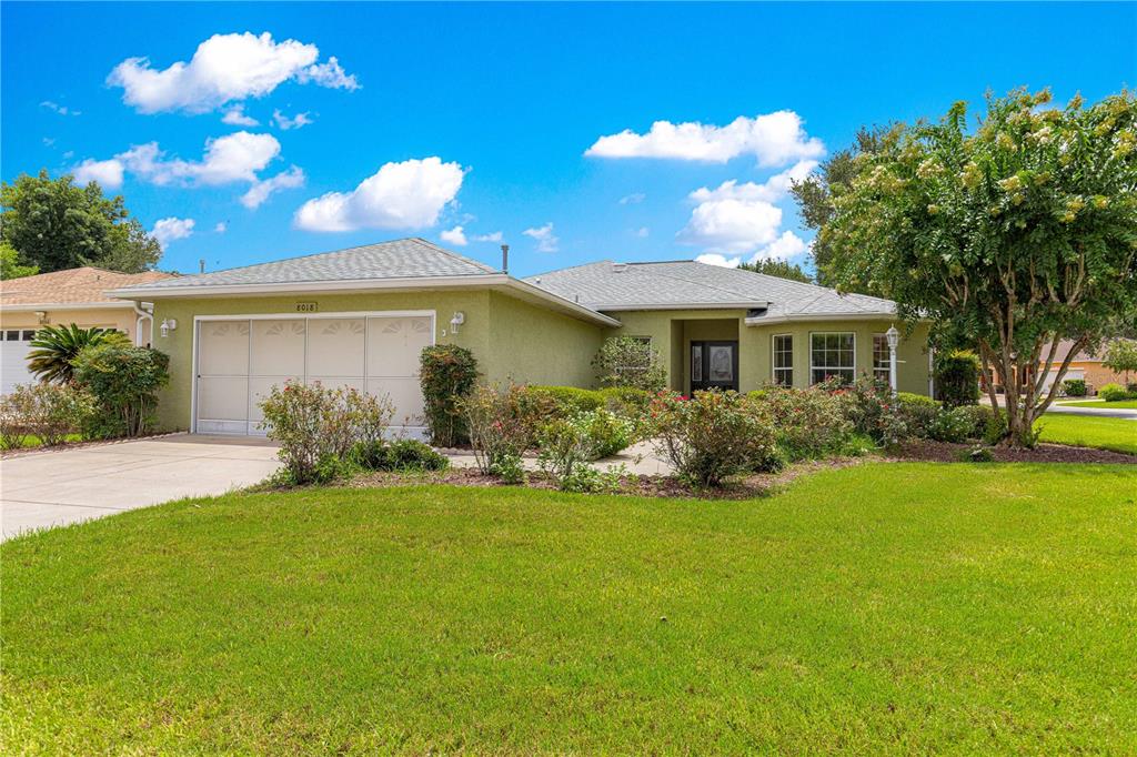 A single-story house with a light green stucco exterior, a two-car garage, and a lawn — 8018 SW 83RD PLACE, OCALA, FL