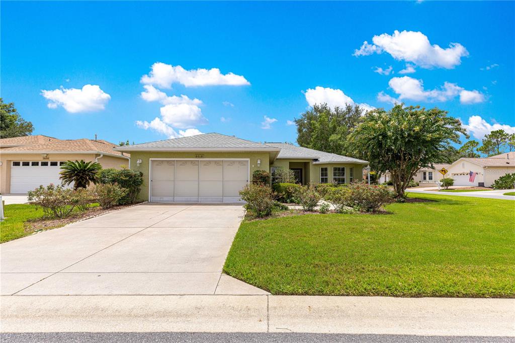 A single-story house with a light green exterior, a two-car garage, and a concrete driveway — 8018 SW 83RD PLACE, OCALA, FL