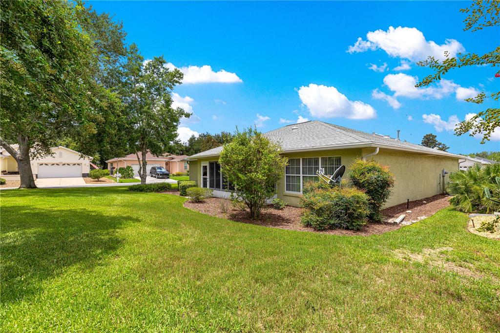 The exterior of a light green house features a screened-in porch and a grassy yard — 8018 SW 83RD PLACE, OCALA, FL
