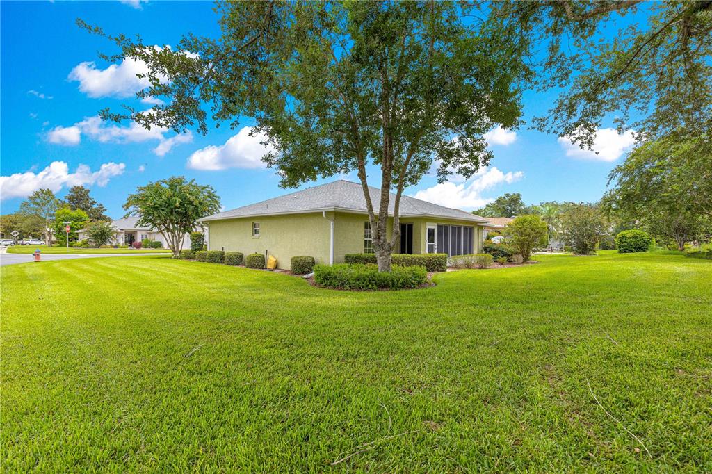 A light green house with a screened-in porch sits on a large, grassy corner lot — 8018 SW 83RD PLACE, OCALA, FL