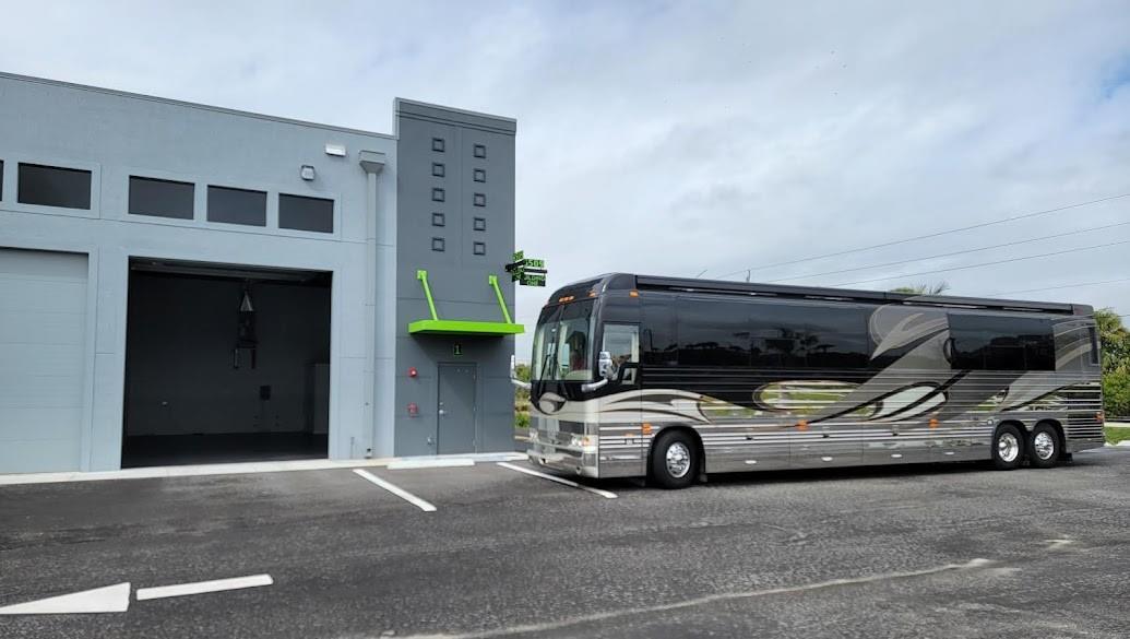 A large luxury motorcoach is parked next to a modern gray industrial building with green accents — 6509 St Lucie Boulevard # 2, Fort Pierce FL 34951, FORT PIERCE, FL