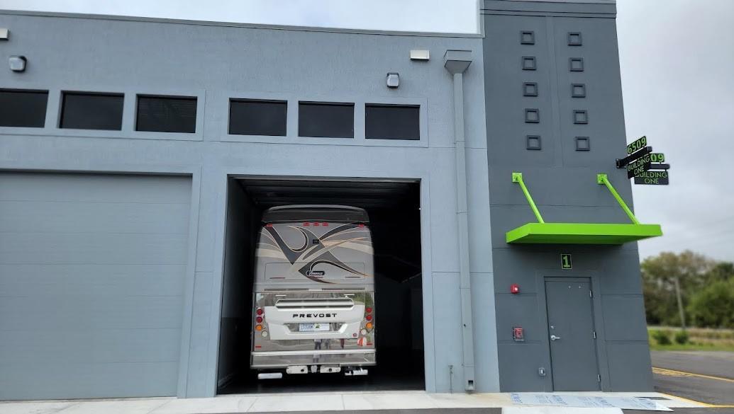A Prevost motorcoach is parked inside a bay of a modern gray industrial building — 6509 St Lucie Boulevard # 2, Fort Pierce FL 34951, FORT PIERCE, FL
