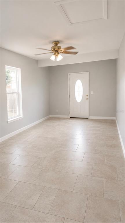 An empty room with light gray walls, tile flooring, a ceiling fan, and a front door — 783 CORNELIA COURT, ORLANDO, FL