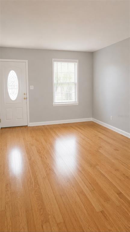 An empty room with light gray walls, hardwood flooring, and a white front door — 783 CORNELIA COURT, ORLANDO, FL