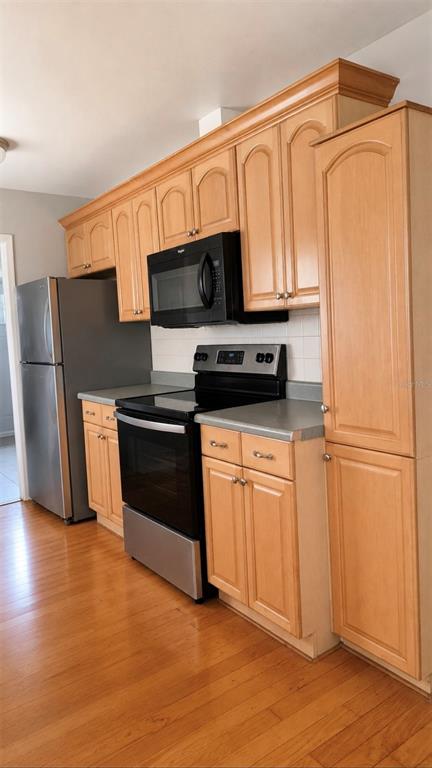 A kitchen features light wood cabinets, stainless steel appliances, and hardwood flooring — 783 CORNELIA COURT, ORLANDO, FL