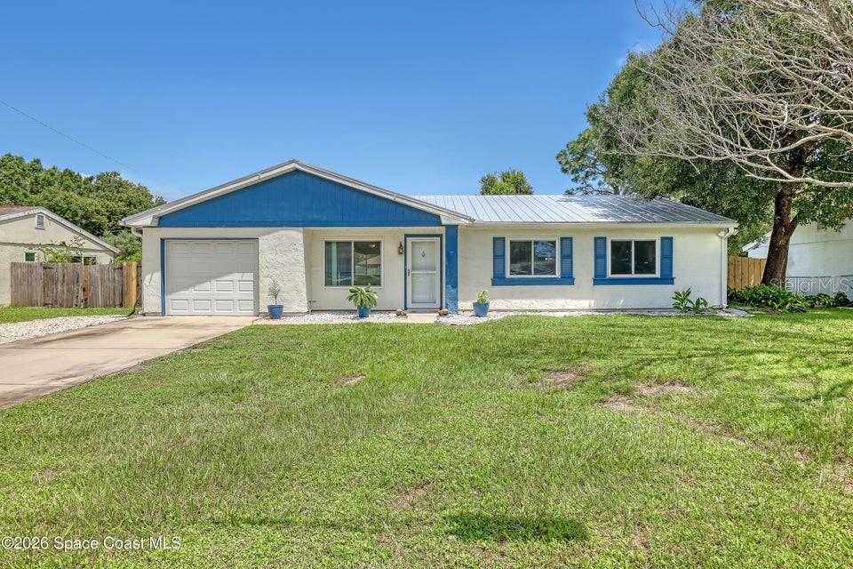 A single-story house with a white stucco exterior, blue trim, and a metal roof — 1671 CHARLES BOULEVARD NE, PALM BAY, FL