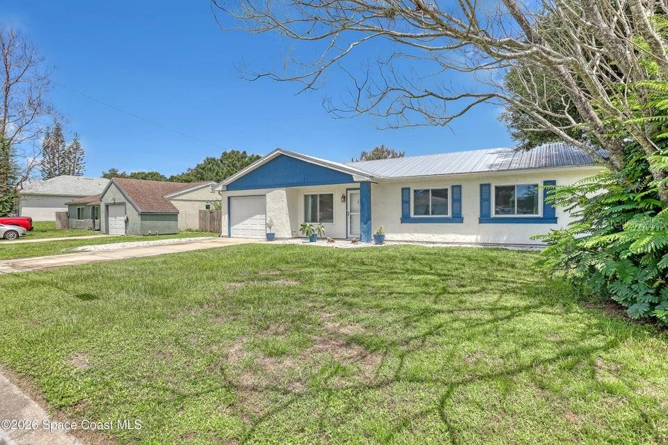 A single-story house with a white stucco exterior, blue trim, and a metal roof — 1671 CHARLES BOULEVARD NE, PALM BAY, FL