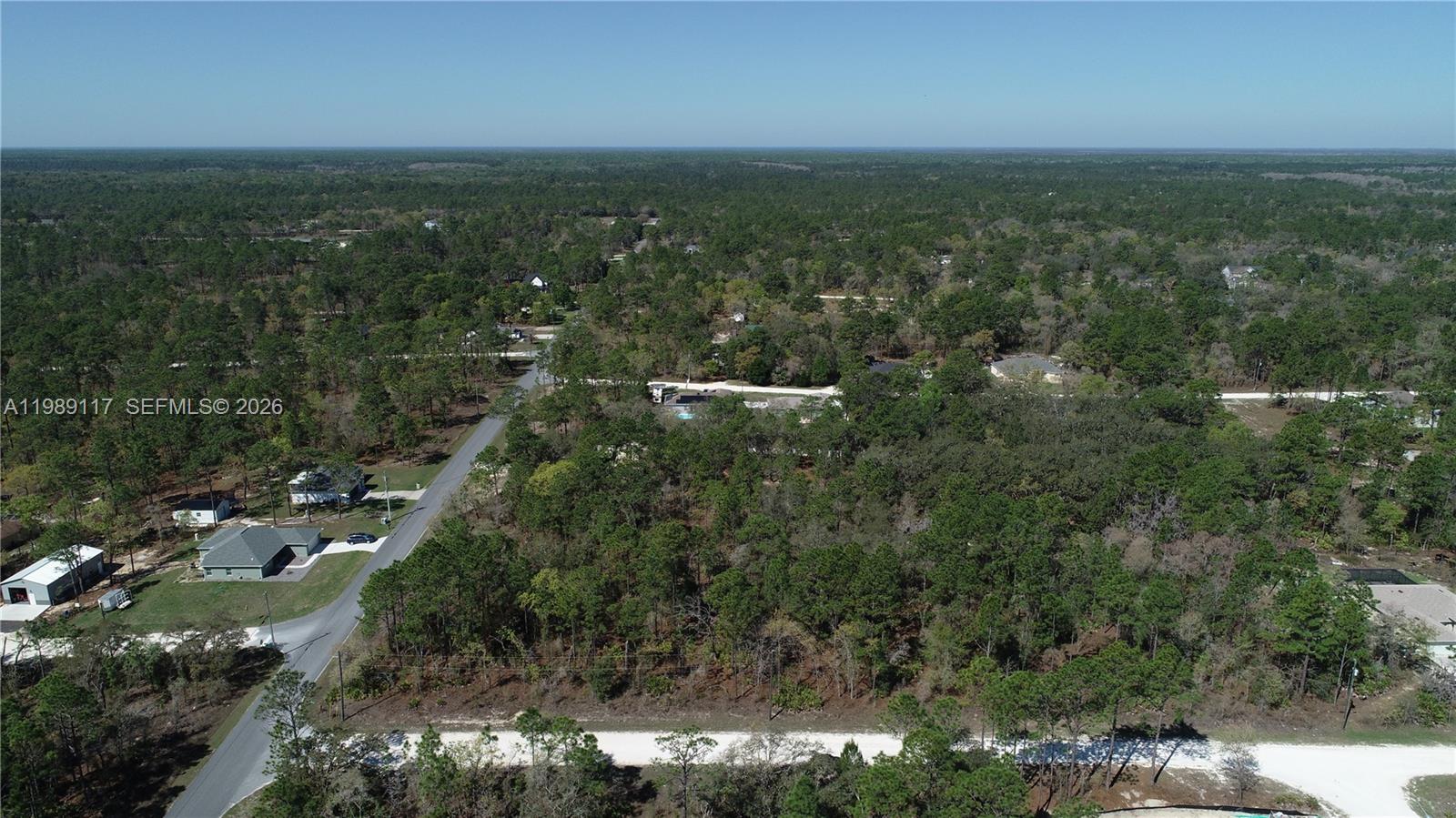 An aerial view shows a wooded residential area with scattered houses and paved roads — 0 Wood Own Ave and Malibar Rd, Other City - In The State Of Florida FL 34614, OTHER CITY - IN THE STATE OF FLORIDA, FL