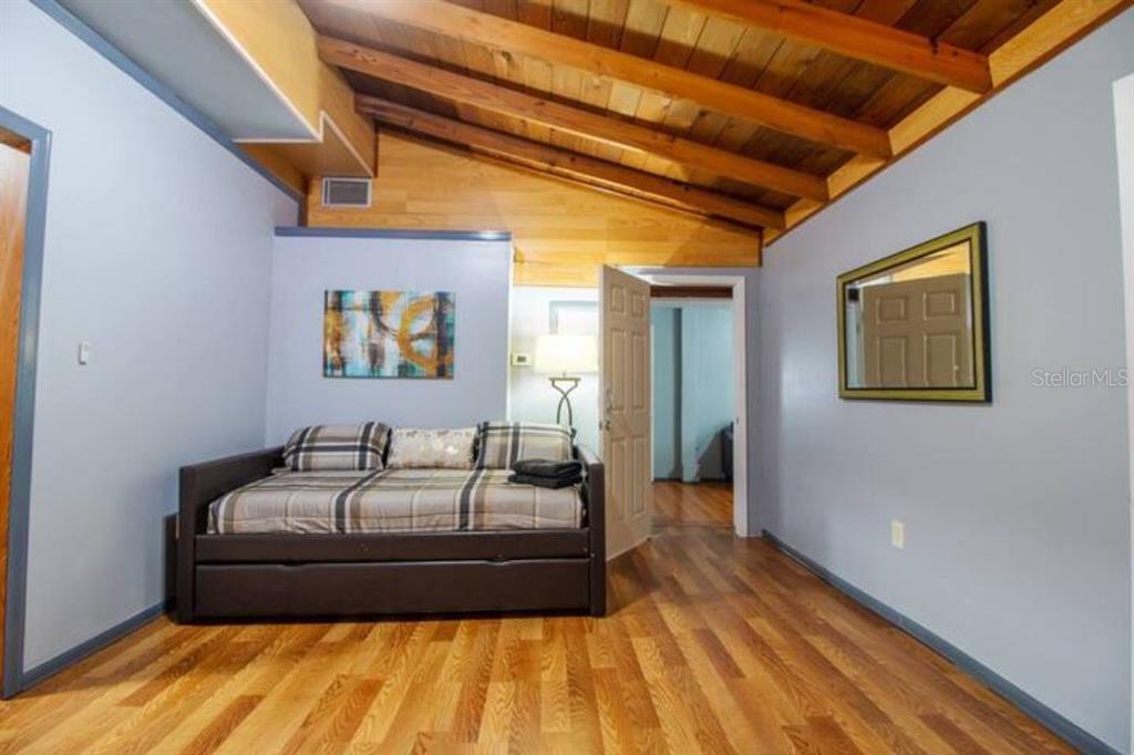 A bedroom with a daybed, wood-plank vaulted ceiling, and hardwood floors — 1731 GRAYSON DR UNIT 1, ORLANDO, FL