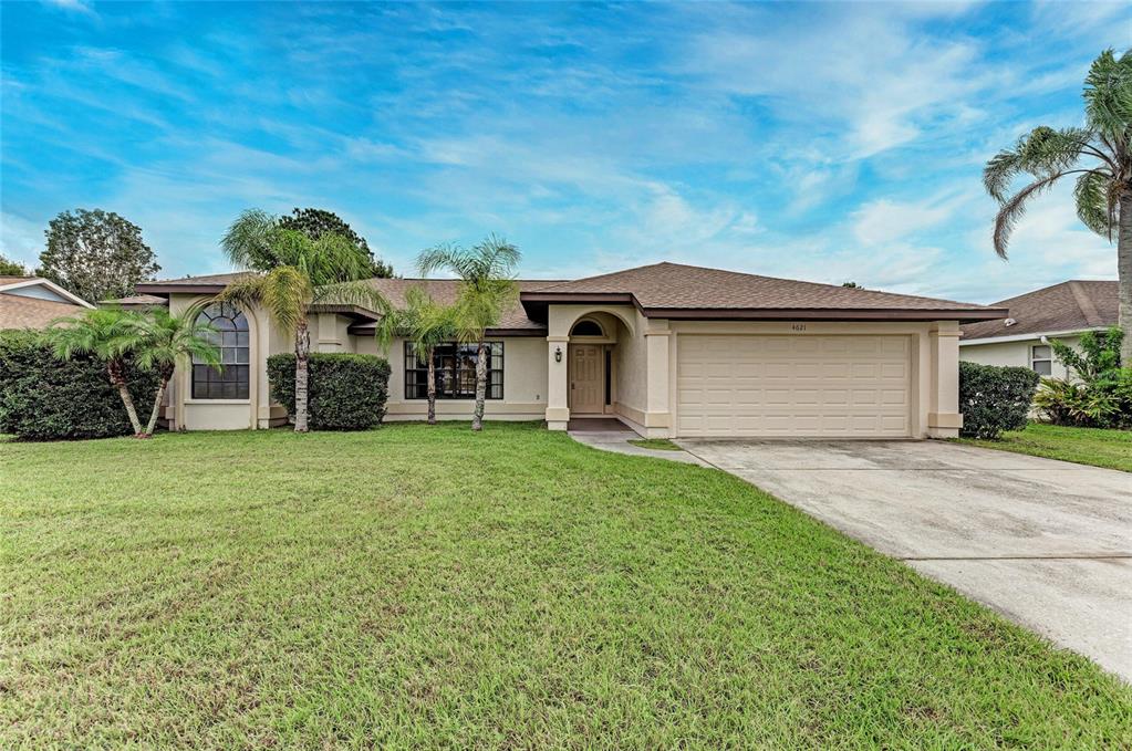A single-story house with a beige stucco exterior, a two-car garage, and palm trees — 4621 35TH COURT E, BRADENTON, FL