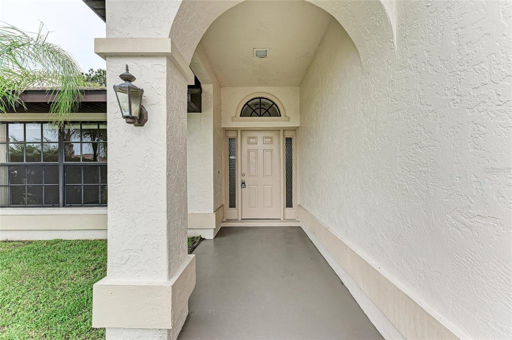 A covered entryway features a beige front door with sidelights and an arched transom window — 4621 35TH COURT E, BRADENTON, FL