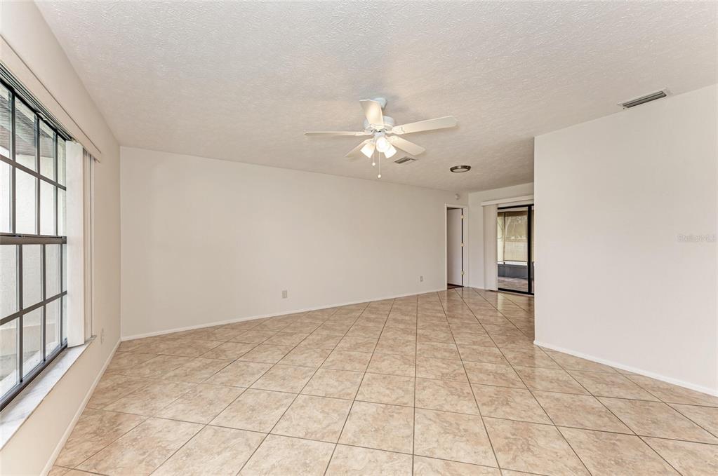 An empty room with beige tile flooring, a ceiling fan, and a large window — 4621 35TH COURT E, BRADENTON, FL