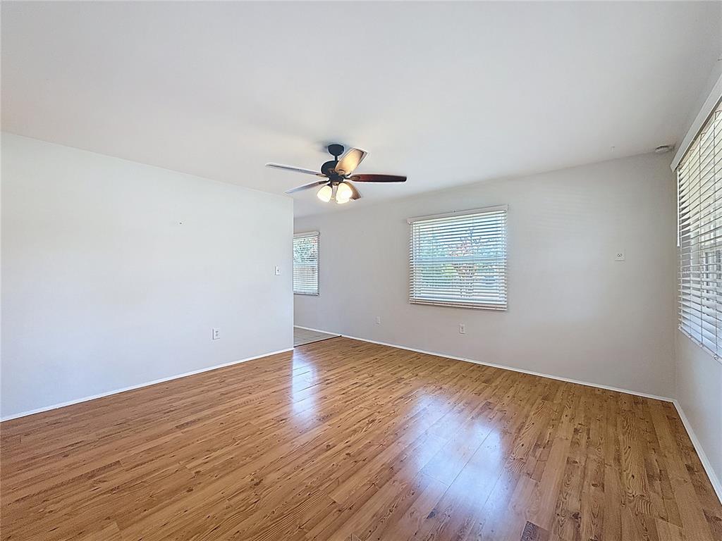 An empty room features light-colored walls, hardwood flooring, a ceiling fan, and two windows — 5326 18TH AVENUE S, GULFPORT, FL