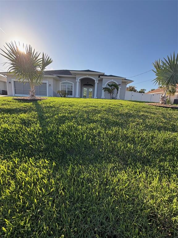 A low-angle view of a single-story house with a green lawn and two palm trees — 2927 BELLEVILLE TERRACE, NORTH PORT, FL