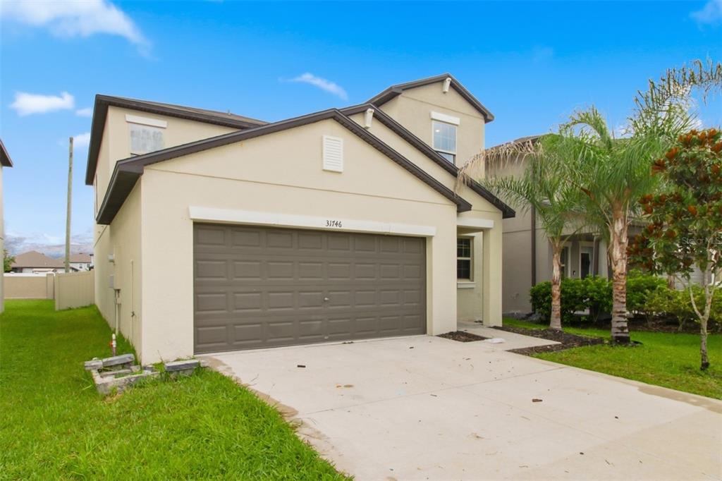 A two-story house with a beige stucco exterior and a two-car garage — 31746 BARREL WAVE WAY, WESLEY CHAPEL, FL