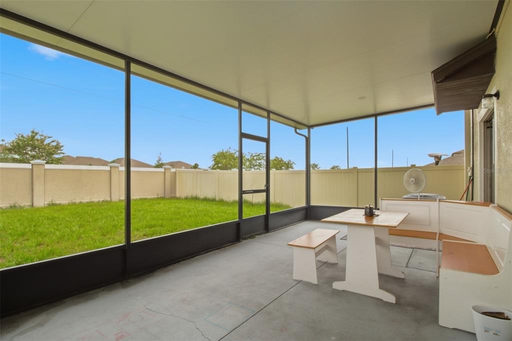 A screened-in patio with a concrete floor, a dining set, and a view of the backyard — 31746 BARREL WAVE WAY, WESLEY CHAPEL, FL