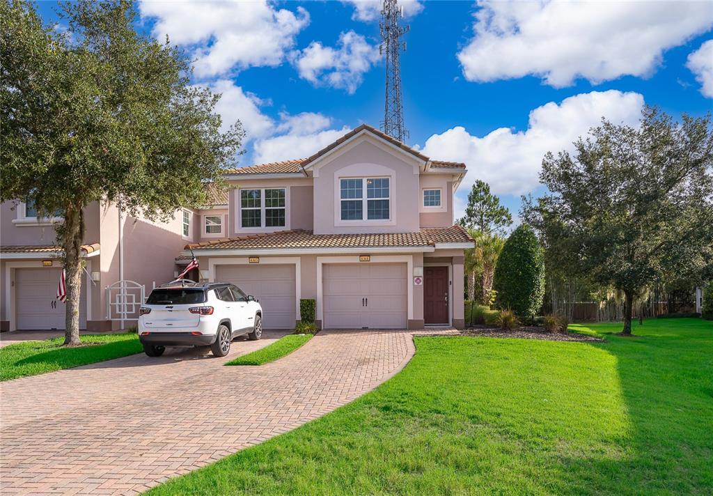 A two-story townhouse with a paver driveway, two garage doors, and a white SUV parked — 8301 BELLA VIDA CIRCLE UNIT 8301, DAVENPORT, FL