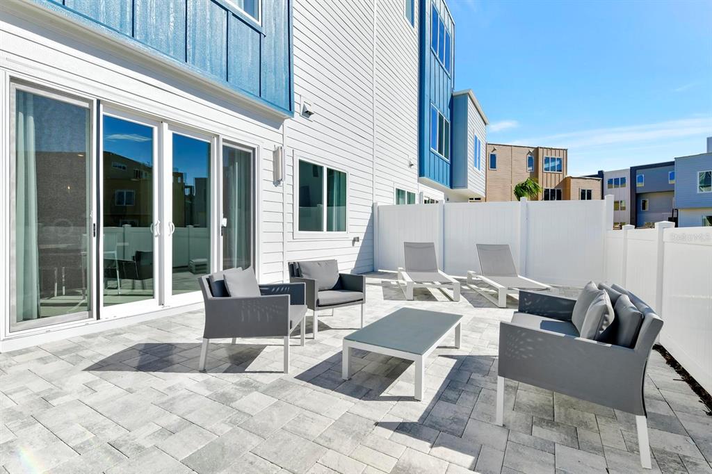 A paved patio features outdoor furniture and lounge chairs against the side of a house — 7740 SANDY RIDGE DRIVE UNIT 136, REUNION, FL