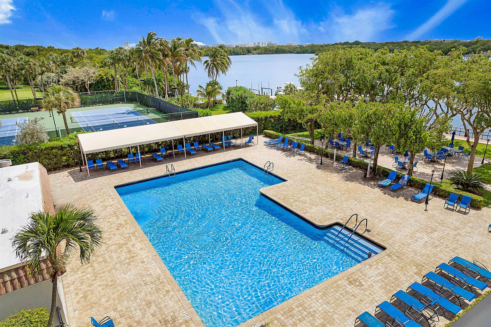 An aerial view of a swimming pool with lounge chairs, a tennis court, and water — 2121 N Ocean Boulevard # 407w, Boca Raton FL 33431, BOCA RATON, FL