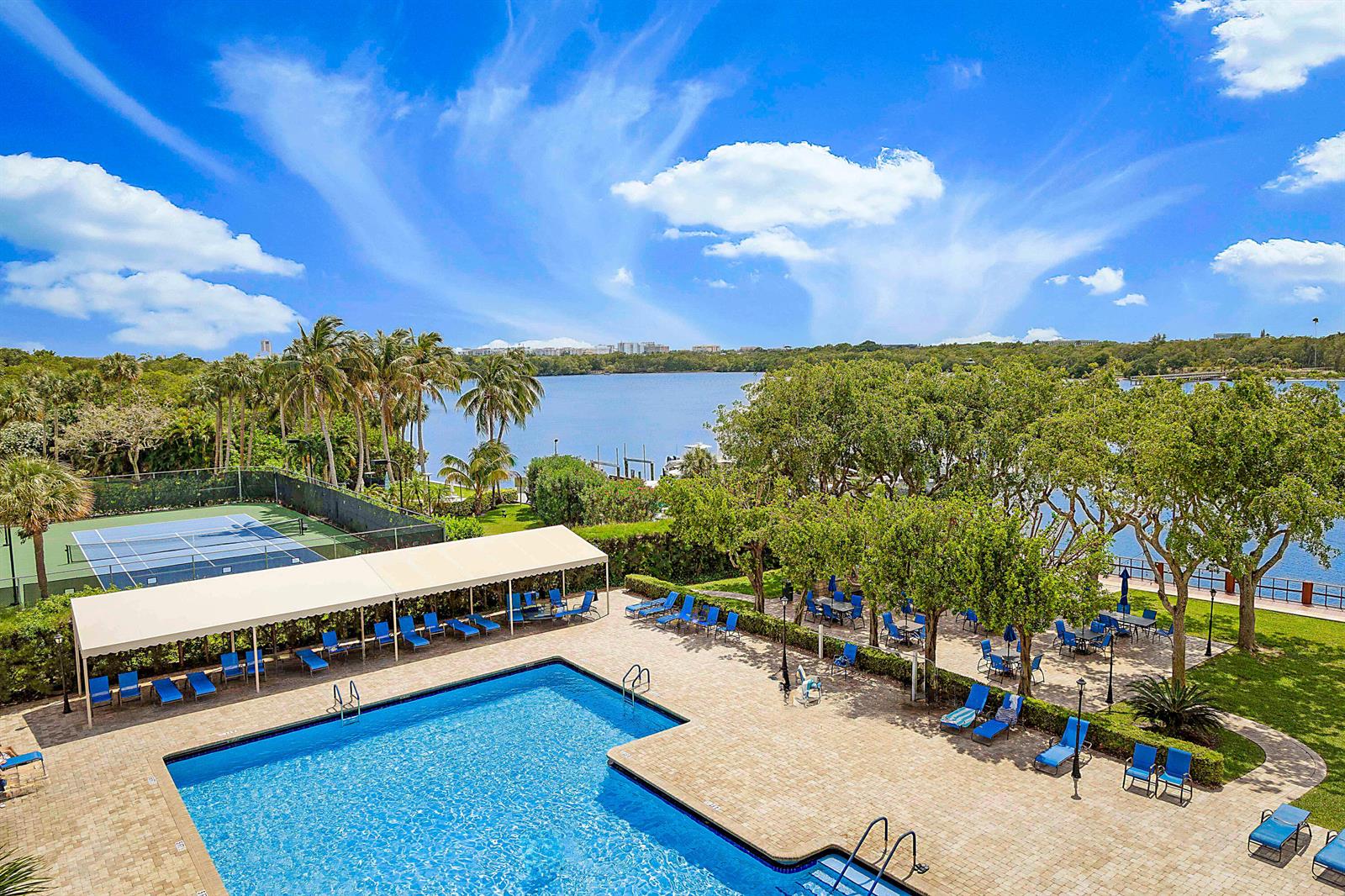 An elevated view of a swimming pool, tennis court, and patio area overlooking a lake — 2121 N Ocean Boulevard # 407w, Boca Raton FL 33431, BOCA RATON, FL
