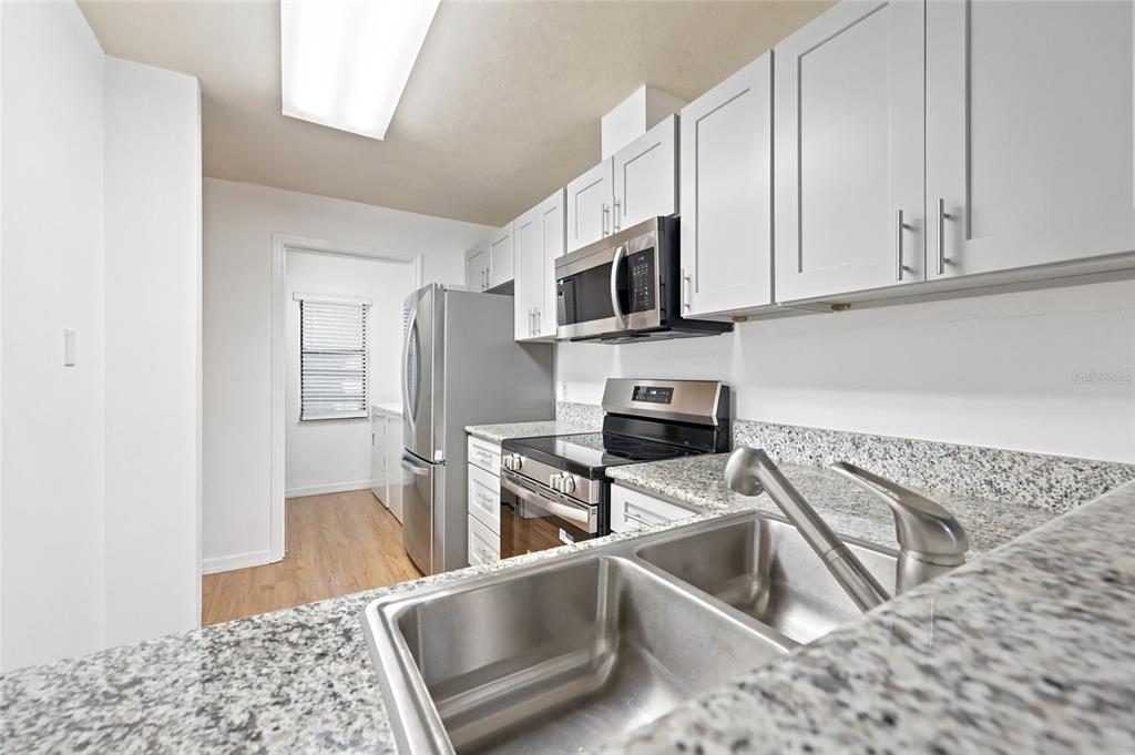 A kitchen features white cabinets, granite countertops, stainless steel appliances, and a double-basin sink — 3405 NW 52ND TERRACE, GAINESVILLE, FL
