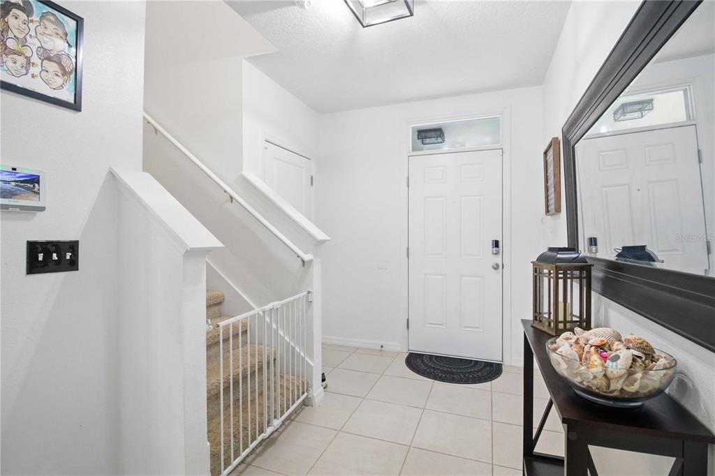 An entryway features a staircase with a safety gate, tile flooring, and a console table — 10230 GEESE TRAIL CIRCLE, SUN CITY CENTER, FL