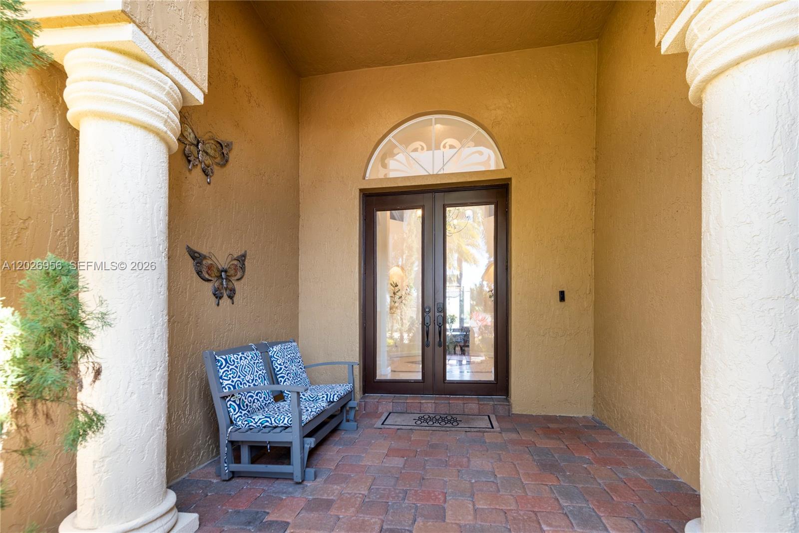A covered entryway features a brick floor, two columns, a bench, and double glass doors — 18991 SW 32nd St, Miramar FL 33029, MIRAMAR, FL