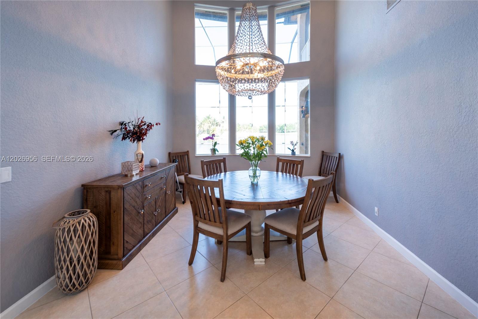 A dining area features a round wooden table, chairs, a sideboard, and a large chandelier — 18991 SW 32nd St, Miramar FL 33029, MIRAMAR, FL