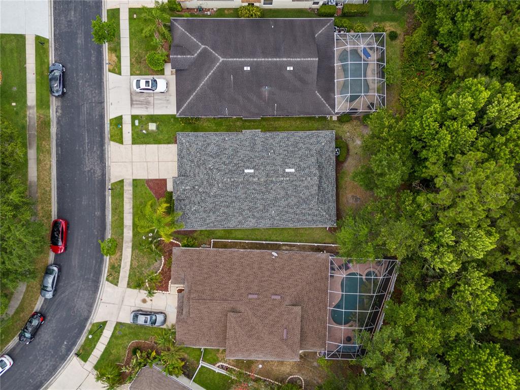 An aerial view shows three suburban houses with driveways, pools, and surrounding trees — 3056 SUNWATCH DRIVE, WESLEY CHAPEL, FL