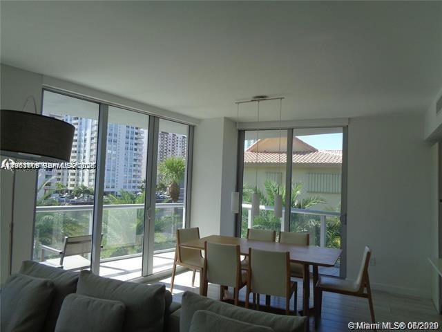 A dining area with a wooden table and chairs sits before large windows overlooking buildings — 2600 E Hallandale Beach Blvd # T301, Hallandale Beach FL 33009, HALLANDALE BEACH, FL