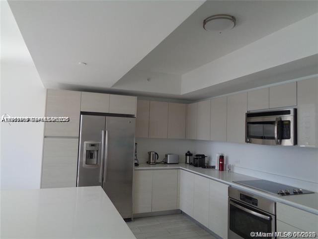 A modern kitchen features light-toned cabinetry, stainless steel appliances, and a white countertop island — 2600 E Hallandale Beach Blvd # T301, Hallandale Beach FL 33009, HALLANDALE BEACH, FL
