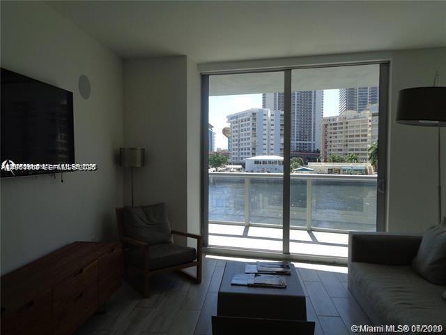 A living room features a television, armchair, sofa, and a balcony overlooking a waterway — 2600 E Hallandale Beach Blvd # T301, Hallandale Beach FL 33009, HALLANDALE BEACH, FL