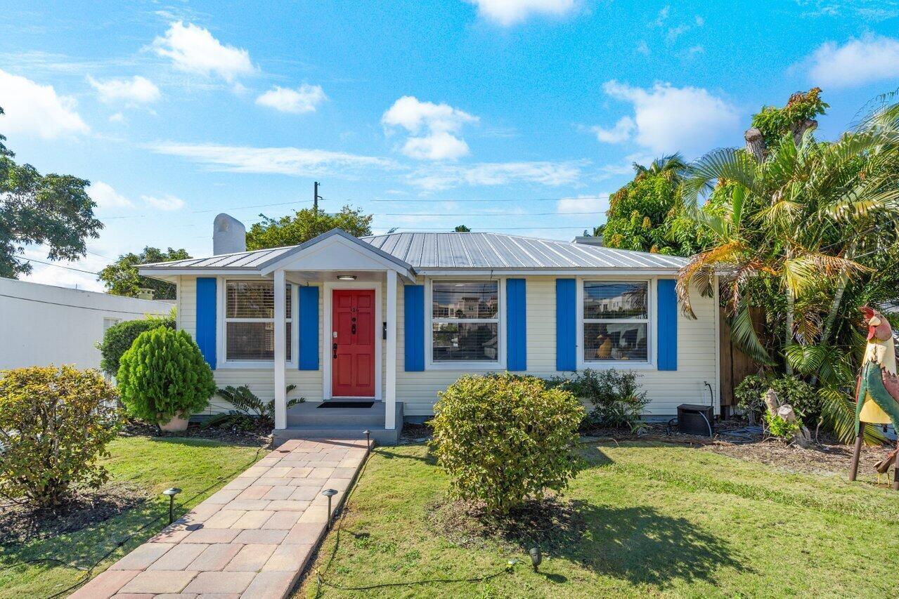 A single-story house with light yellow siding, a red front door, and blue window shutters — 126 NE 4th Avenue, Delray Beach FL 33483, DELRAY BEACH, FL