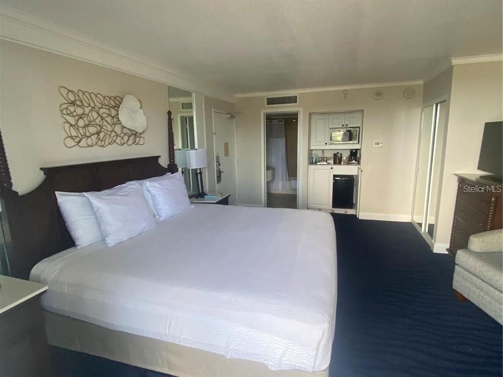 A bedroom features a king bed, a small kitchenette, and a dark blue carpet — 5500 GULF BOULEVARD UNIT 4256, ST PETERSBURG, FL
