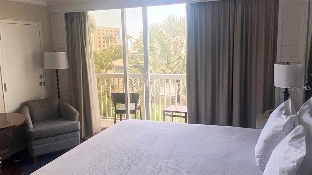 A bedroom features a bed, an armchair, and a sliding glass door leading to a balcony — 5500 GULF BOULEVARD UNIT 4256, ST PETERSBURG, FL