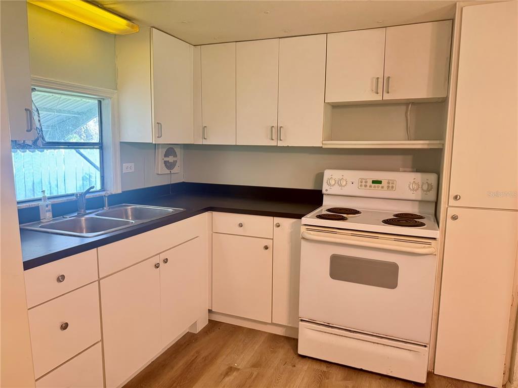 A kitchen features white cabinets, a black countertop, a double sink, and a white stove — 3405 FREMONT LANE, SPRING HILL, FL